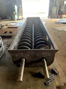 Twin screw conveyor shafts installed in trough system for bulk material handling