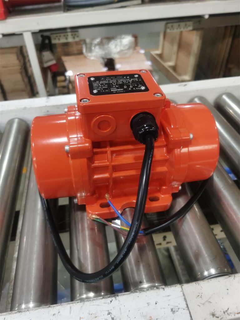 Overall view of a compact industrial vibration motor for bulk material handling equipment