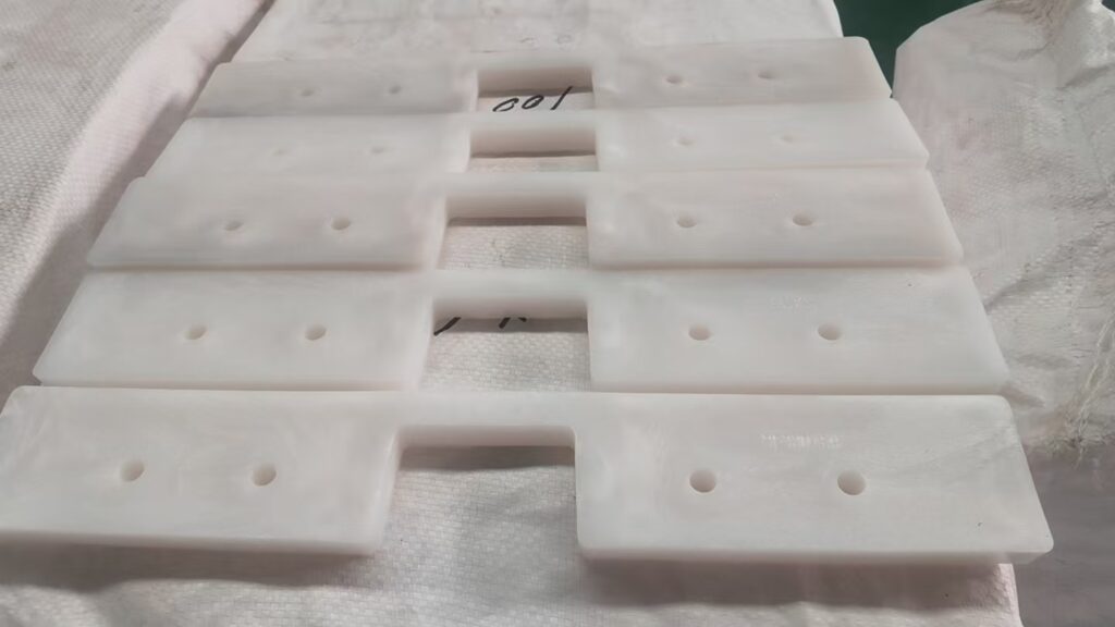 Close-up view of custom UHMWPE drag conveyor flights showing the profile and mounting holes