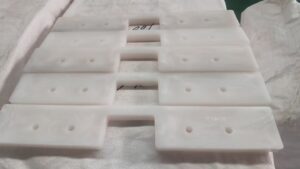 Close-up view of custom UHMWPE drag conveyor flights showing the profile and mounting holes
